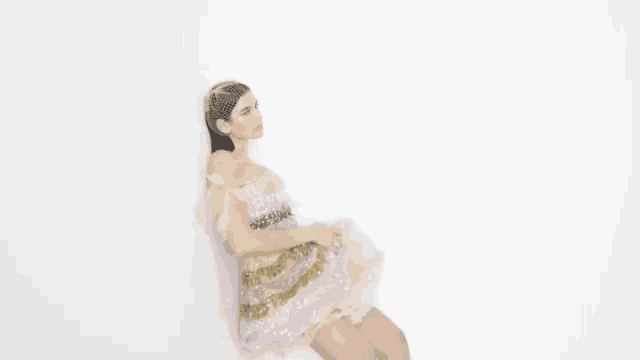 a woman in a dress is leaning against a wall with her legs crossed .