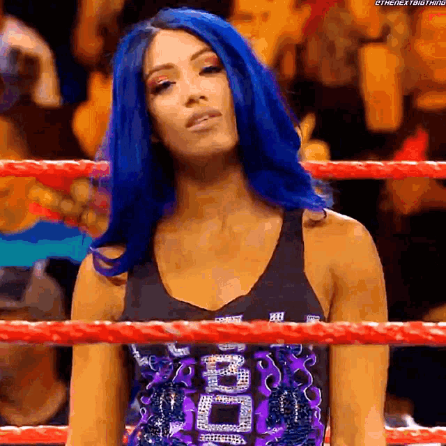 a woman with blue hair is standing in a boxing ring
