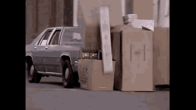 a car is parked next to a pile of cardboard boxes with the numbers 1 and 1 on them .