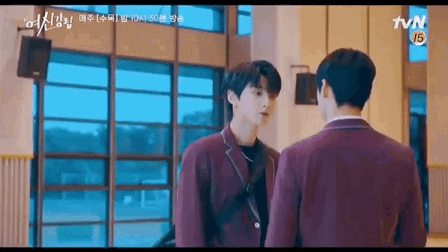 two boys are standing next to each other in a room .