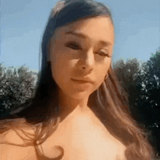 ariana grande is looking at the camera while wearing a crop top and earrings .