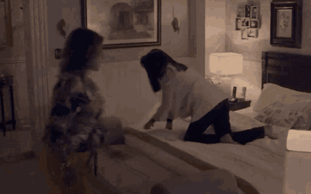 two women are kneeling on a bed in a room