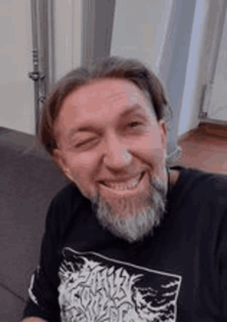 a man with a beard wearing a black shirt is smiling .