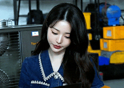 a woman wearing a denim shirt is looking down at something