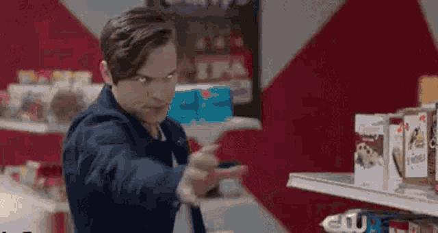 a man is standing in front of a shelf in a store holding a gun .