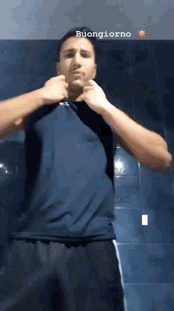 a man in a blue shirt and black shorts is standing in front of a blue wall with the words buongiorno above him