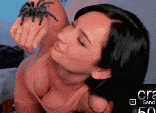 a woman is holding a spider in her hand in front of a screen that says craz send 50