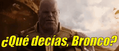 a man with a beard is standing in front of a sign that says ' que decias bronco ? '