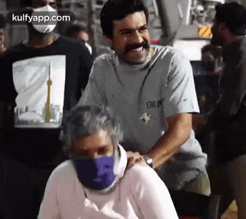a man with a mustache is giving a massage to another man wearing a mask .