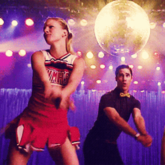 a cheerleader in a vmhs uniform stands next to a man in a bow tie