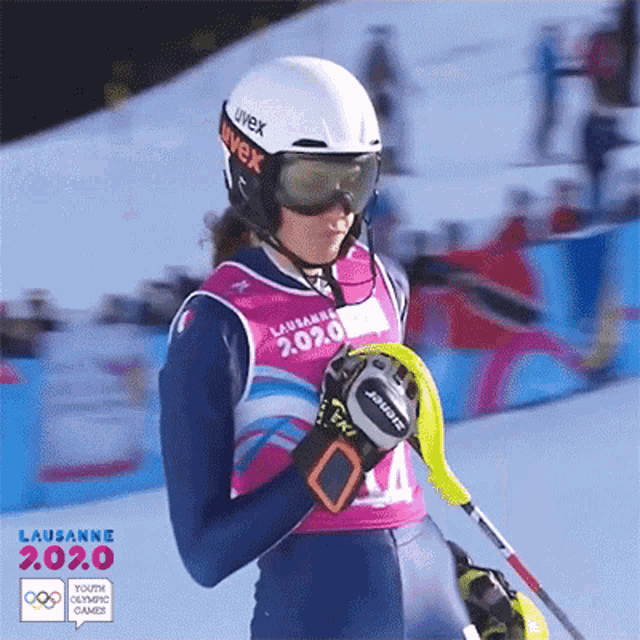 a woman wearing a helmet and goggles stands in front of a sign that says lausanne 2.0.0