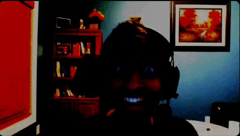 a woman wearing headphones smiles in front of a bookshelf