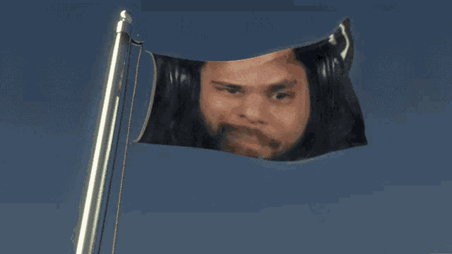 a flag with a man 's face on it is waving in the wind