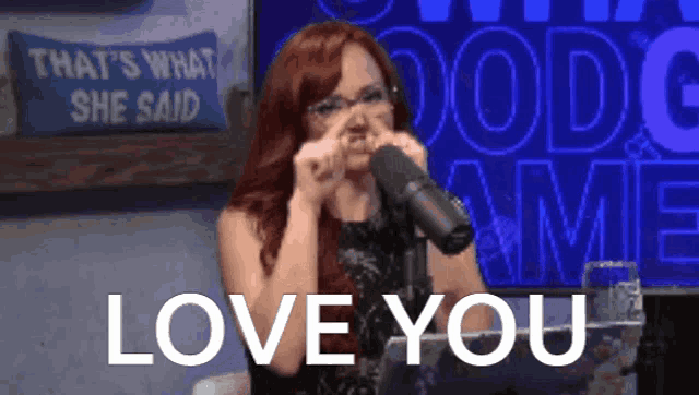 a woman covering her nose in front of a microphone with the words love you written below her