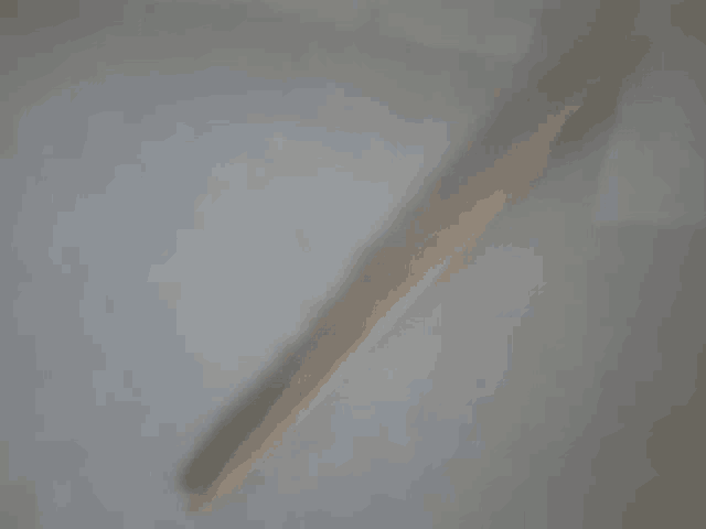 a wooden stick on a white surface with a shadow