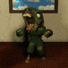 a green monster is standing in a room in front of a picture on the wall .