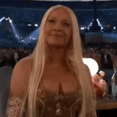 a woman with long blonde hair is standing in front of a crowd of people .