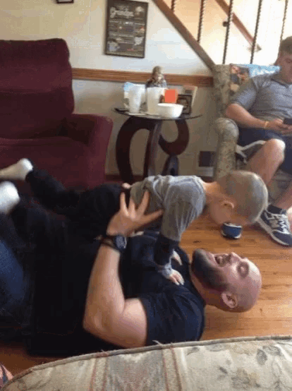 a man is laying on the floor holding a baby in his arms