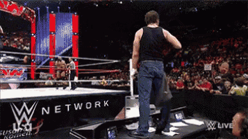 a man in a black tank top is standing in front of a w network sign