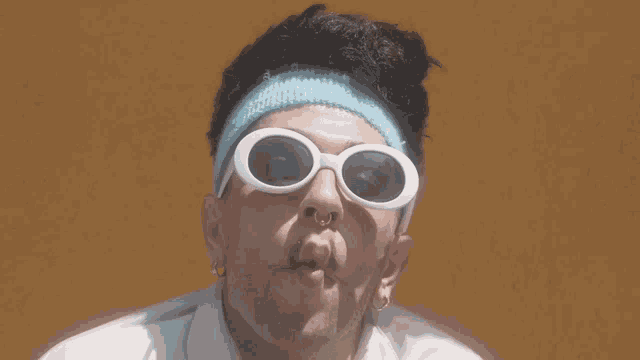 a man wearing sunglasses and a headband makes a face
