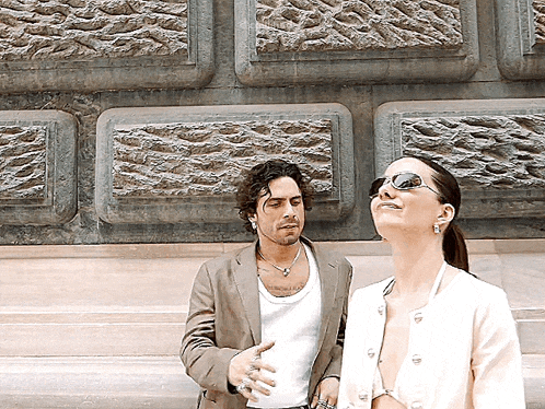 a man and a woman are standing in front of a wall