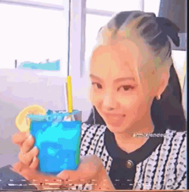 a woman is holding a blue drink with a straw and a lemon slice .
