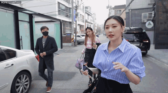 a woman in a blue shirt is walking down the street