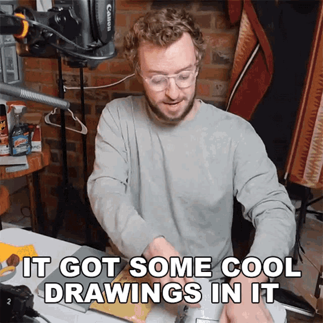 a man sitting at a table with the words it got some cool drawings in it next to him