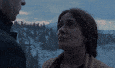 a man and a woman are looking at each other in a snowy scene