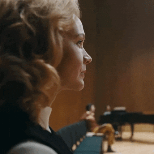 a woman sitting in front of a piano with a blurred background