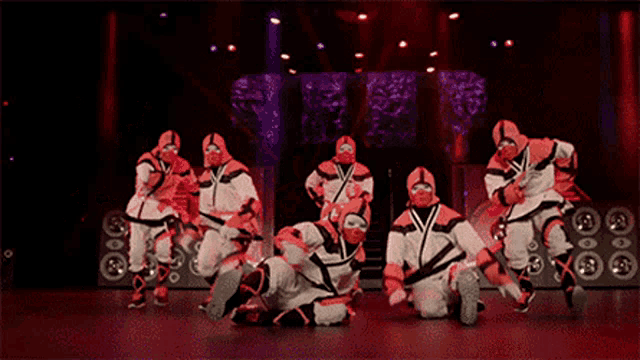 a group of people in ninja costumes are dancing on a stage .
