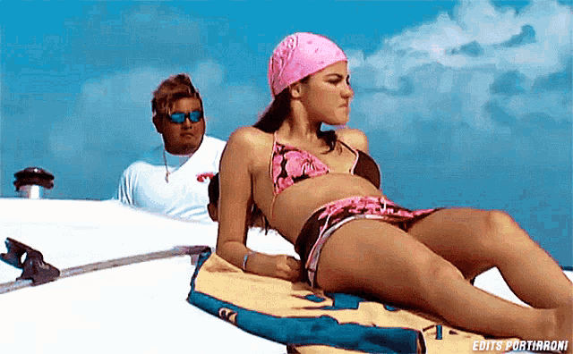 a woman in a bikini is laying on a towel with edits portiaroni written in the upper right corner