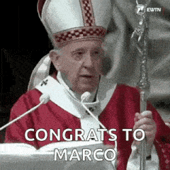 a man in a cardinal 's robe is giving a speech and holding a cane .