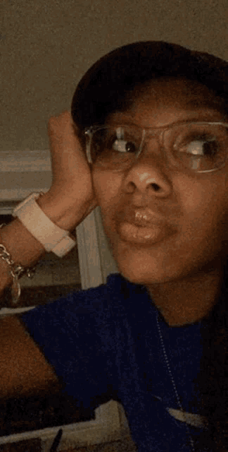 a woman wearing glasses and a blue shirt is looking at the camera .