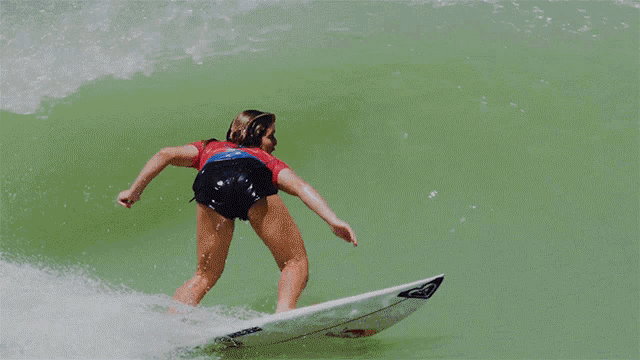 a woman in a hurley shirt is surfing