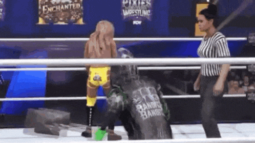 a wrestler is standing in a ring with a referee .