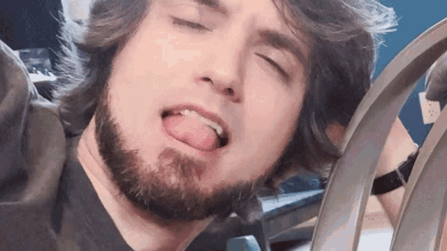 a man with a beard sticks his tongue out