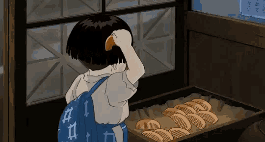 a little girl with a blue backpack is looking at a tray of bread