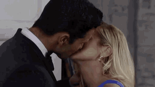 a man and a woman are kissing in front of a wall .