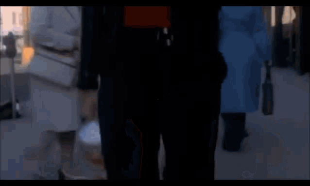 a man in a red shirt and a black jacket is walking down the street