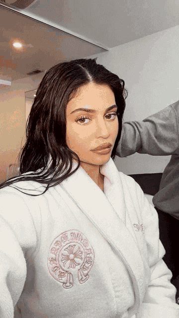 a woman is wearing a white robe with the word chrome hearts on the front