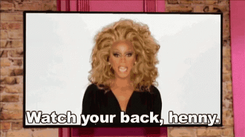 a drag queen says watch your back henny in front of a brick wall