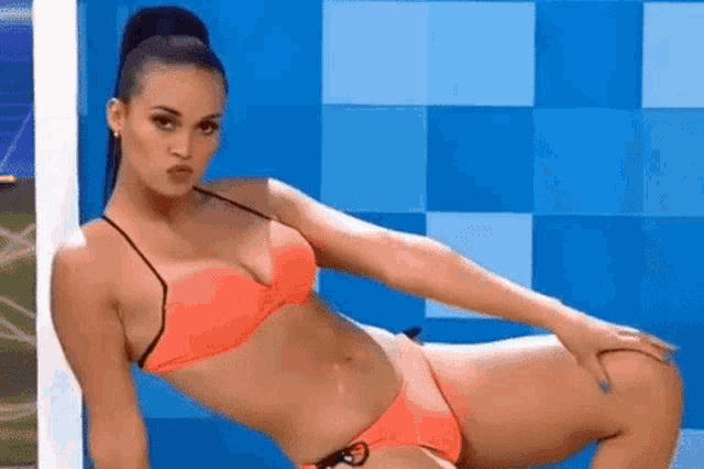 a woman in a bikini is laying on her stomach in front of a blue wall .