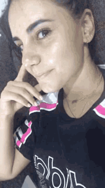 a woman in a black and pink shirt is taking a selfie .
