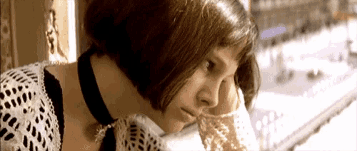 a woman wearing a choker looks out a window