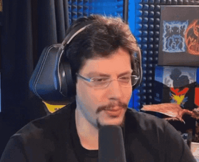 a man wearing glasses and headphones is talking into a microphone .