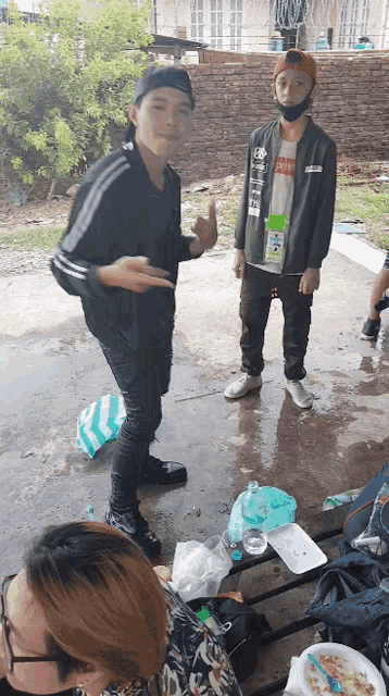 a man wearing a jacket that says ' supreme ' on it stands next to another man