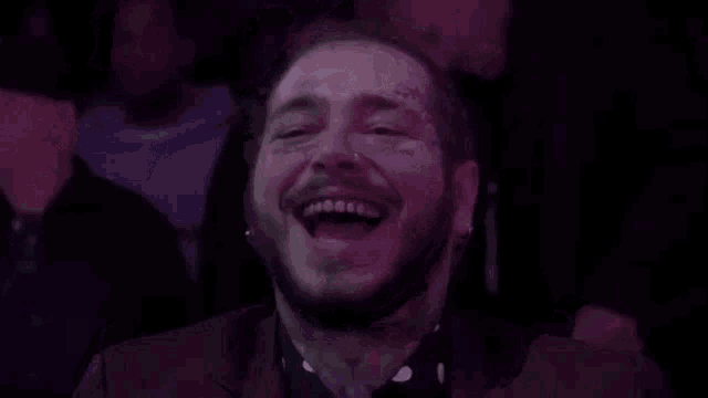 a man in a suit is laughing in a crowd of people .