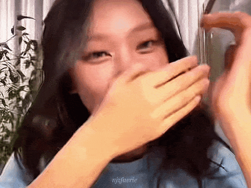 a close up of a woman covering her mouth with her hands and the words njz fuerie visible in the corner