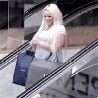 a woman is standing on an escalator holding a bag .